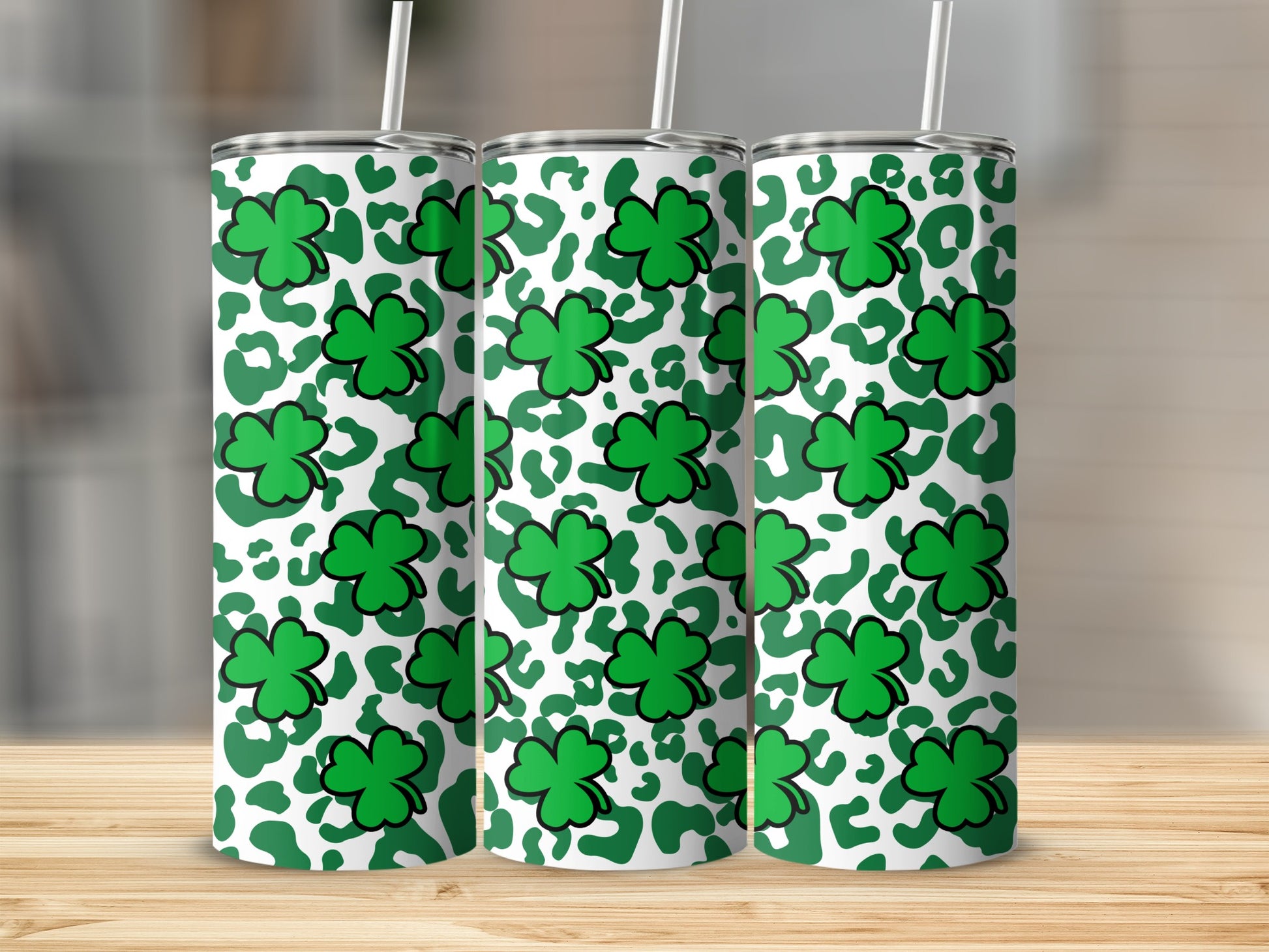 Green shamrocks and white leopard print on three insulated tumblers.