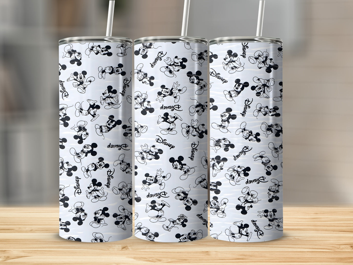 Three Disney Mickey Mouse patterned tumblers on a wooden surface.