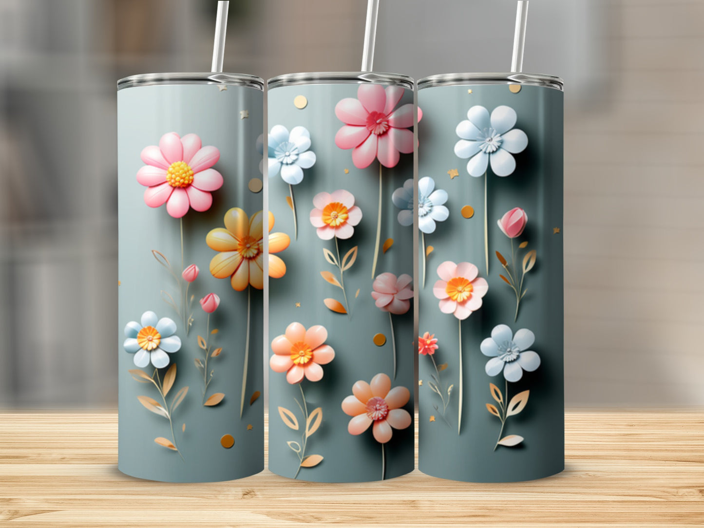 Three tumblers with colorful floral designs and straws stand on a wooden surface.