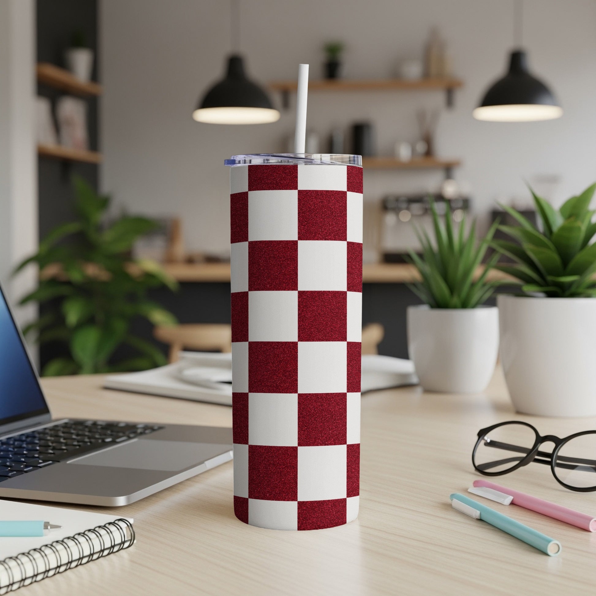 Red and white checkered tumbler with a straw, on a desk.