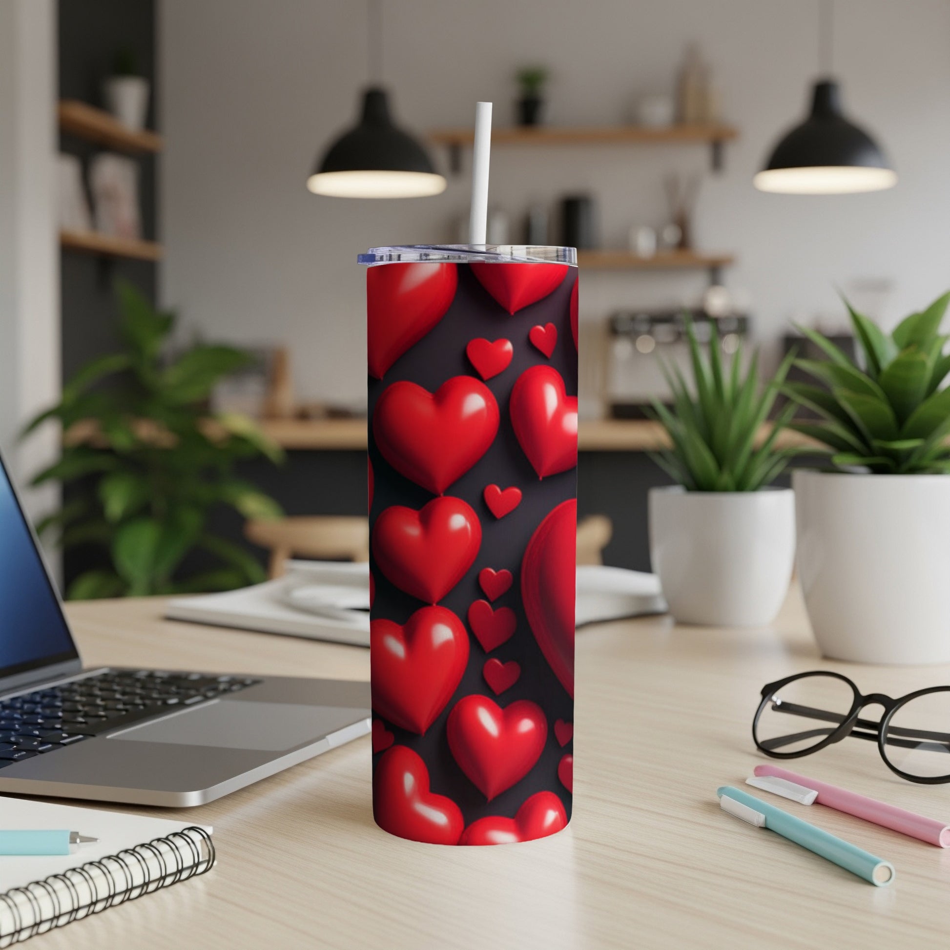 Red hearts pattern on a black tumbler with a straw, on a desk.