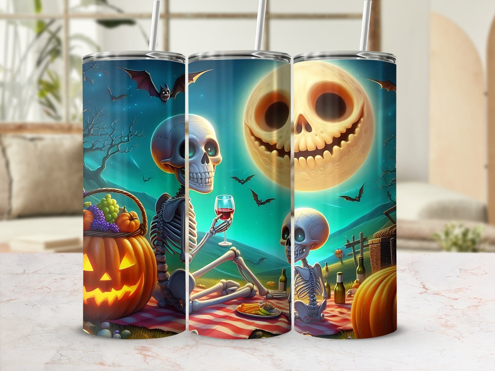 Halloween tumblers with skeletons, bats, and a jack-o'-lantern moon on a picnic blanket.