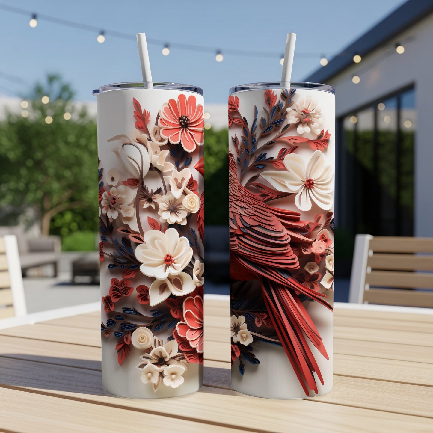 Two tall tumblers featuring a red bird and floral designs on a patio table.