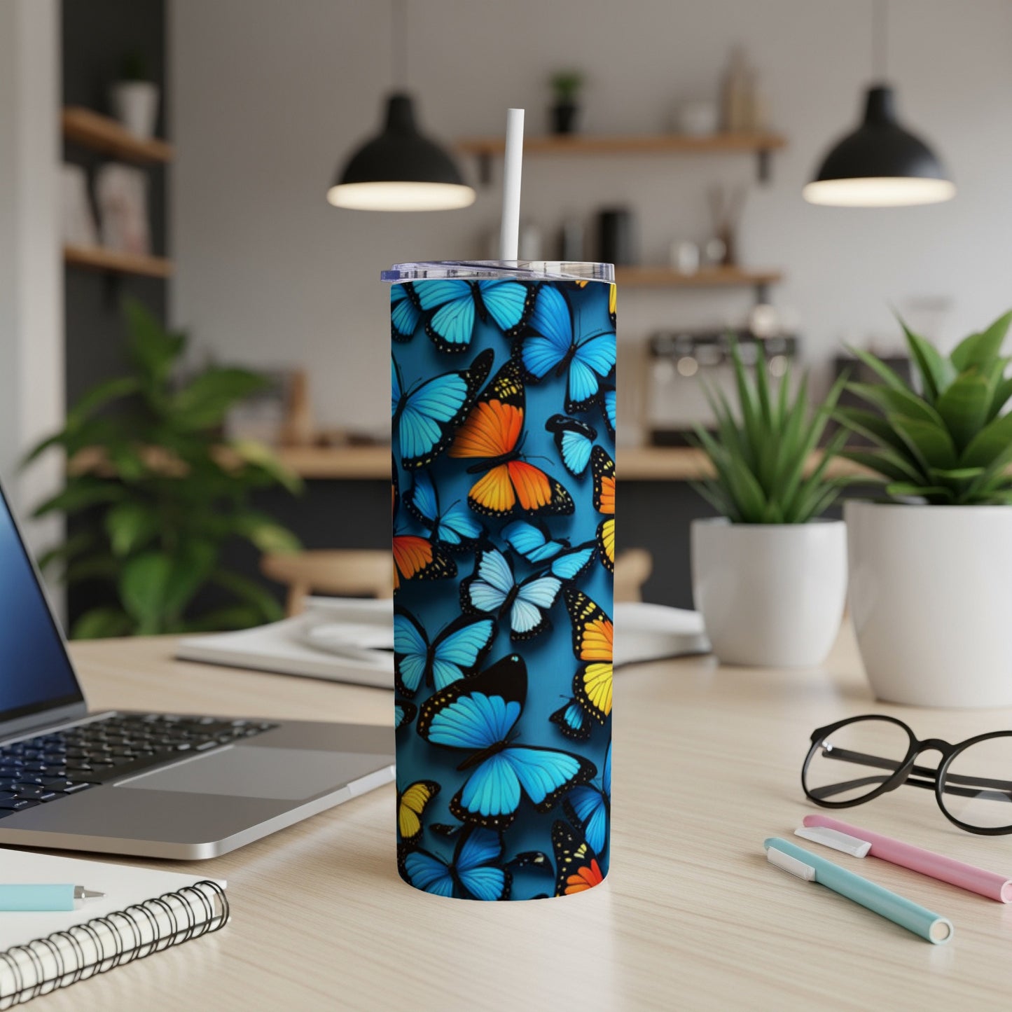 Blue tumbler with colorful butterflies, white straw, on a desk.