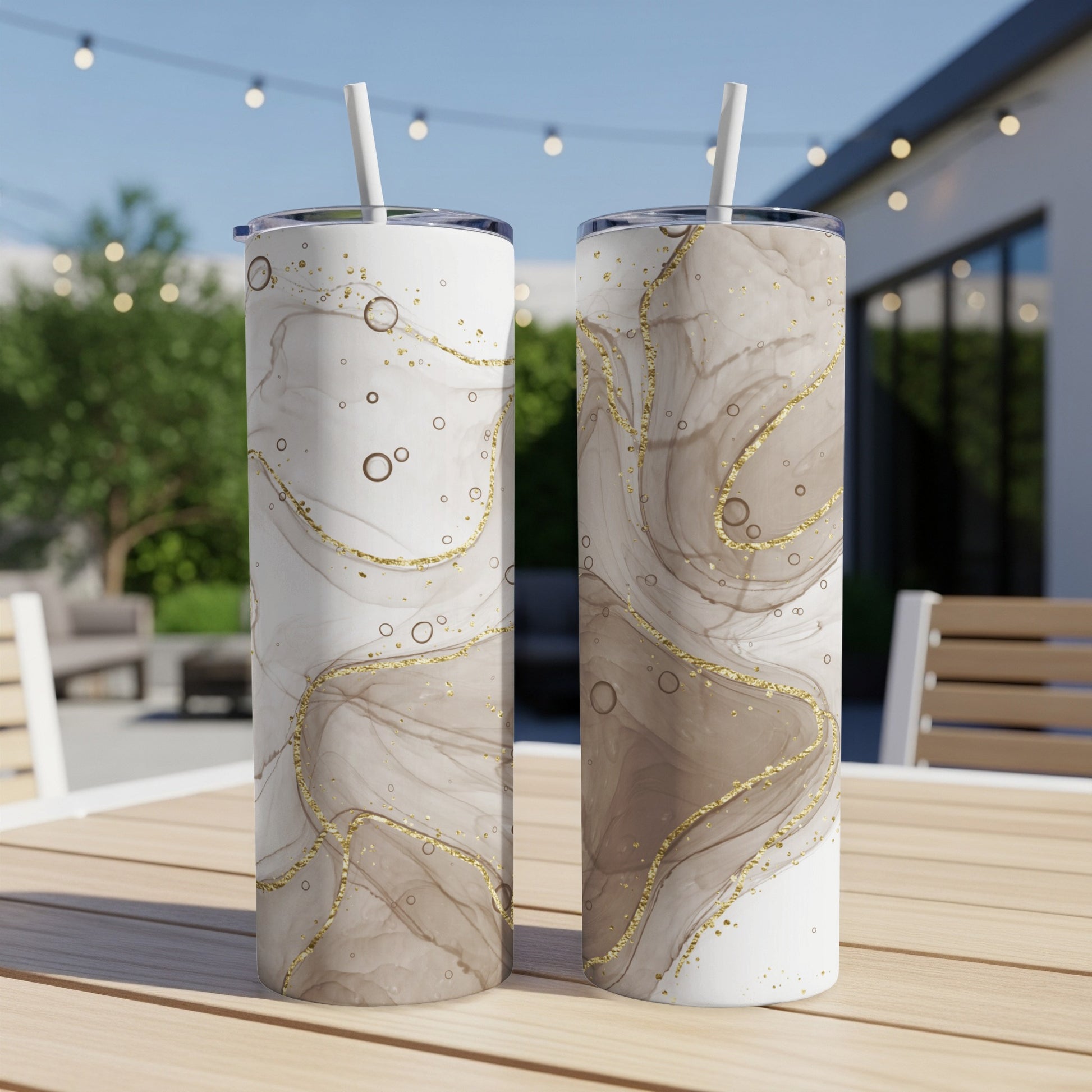 Two tumblers with marbled beige and gold design on a wooden table.