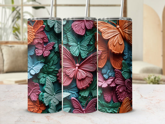 Three tumblers with colorful butterfly patterns against a blurred background.