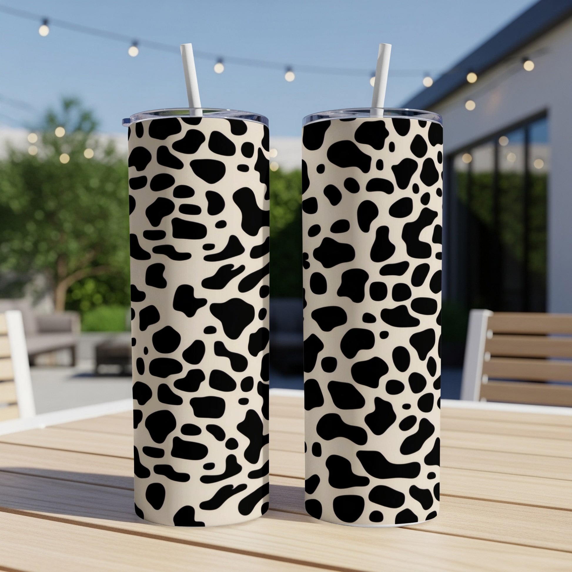 Two tall tumblers with black and white cow print pattern on a table.