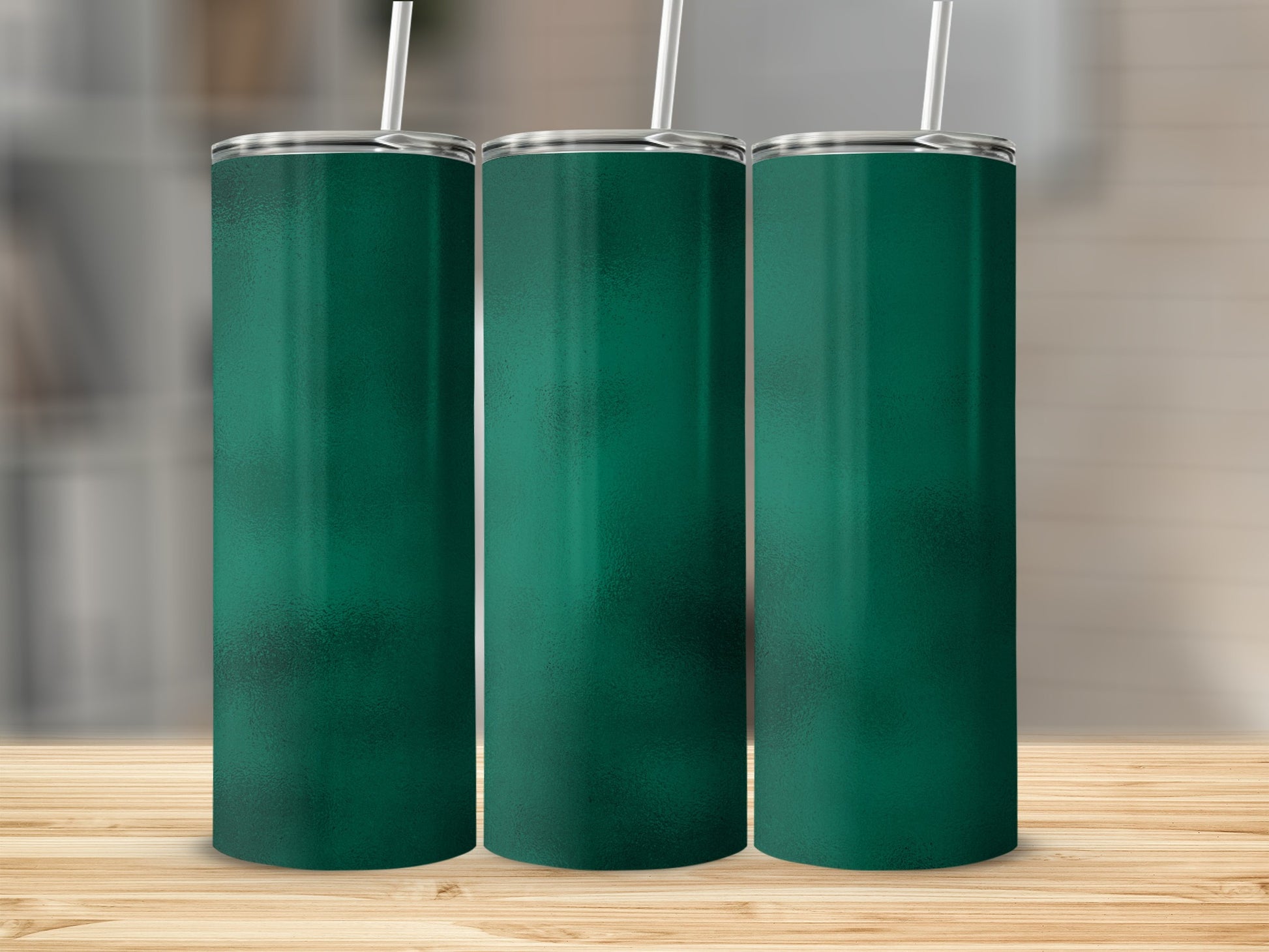 Three metallic green tumblers with straws stand on a wooden surface.