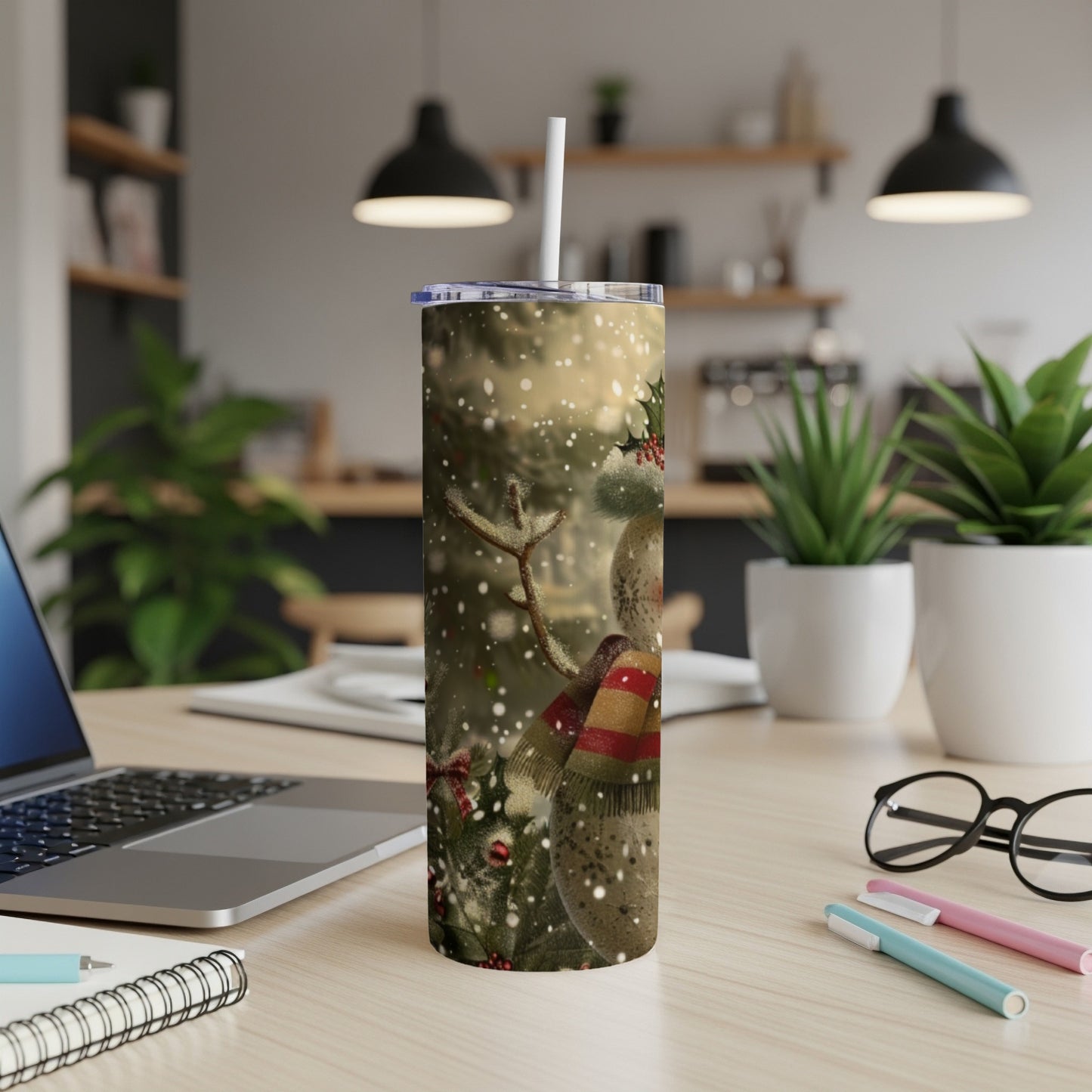 Snowman wearing a scarf on a tumbler with a laptop and office supplies.