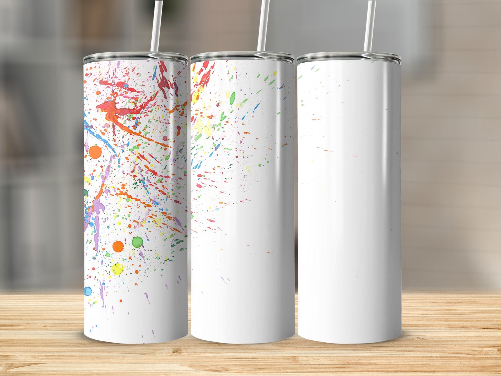 Three tumblers, two with colorful paint splatters, one blank.