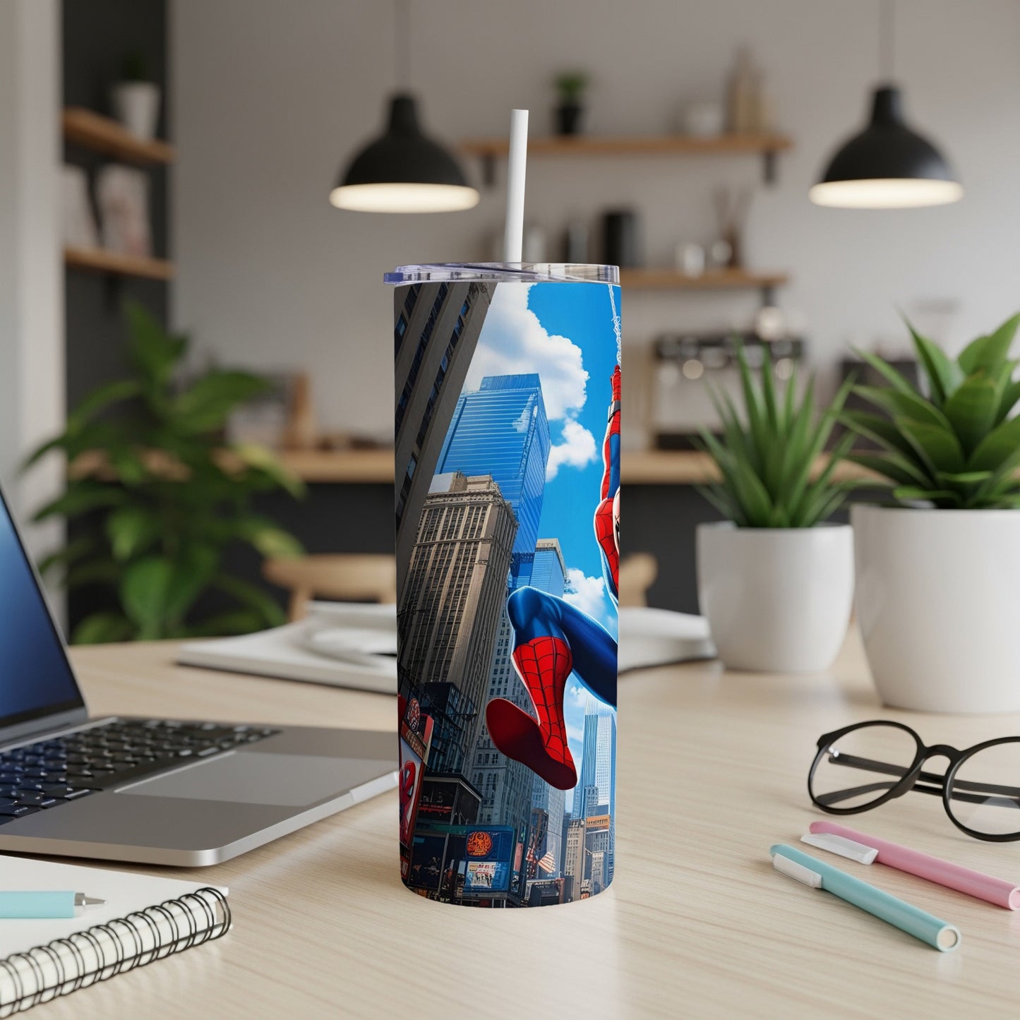 Spider-Man on a cityscape tumbler with a laptop and art supplies.