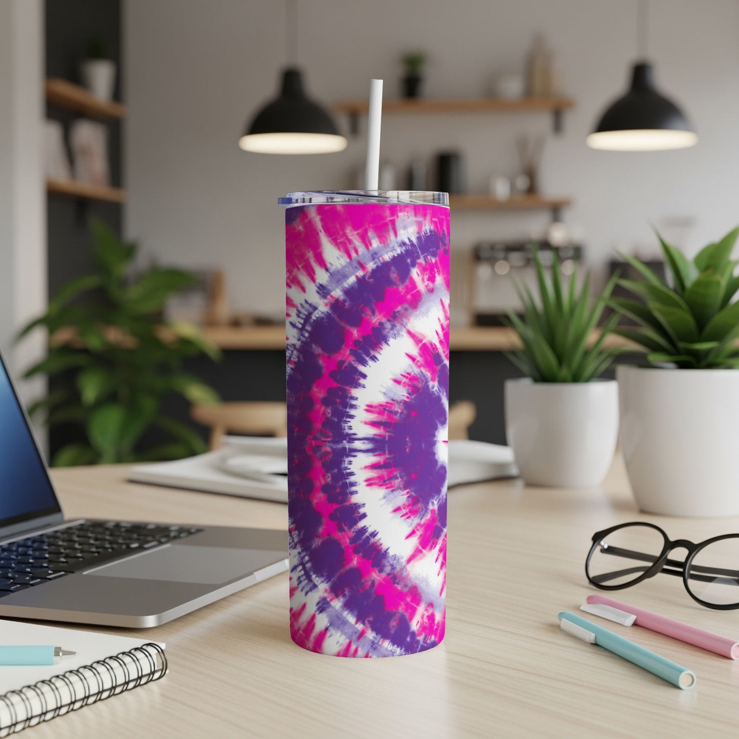 Tumbler with pink and purple tie-dye pattern and white straw on a desk.