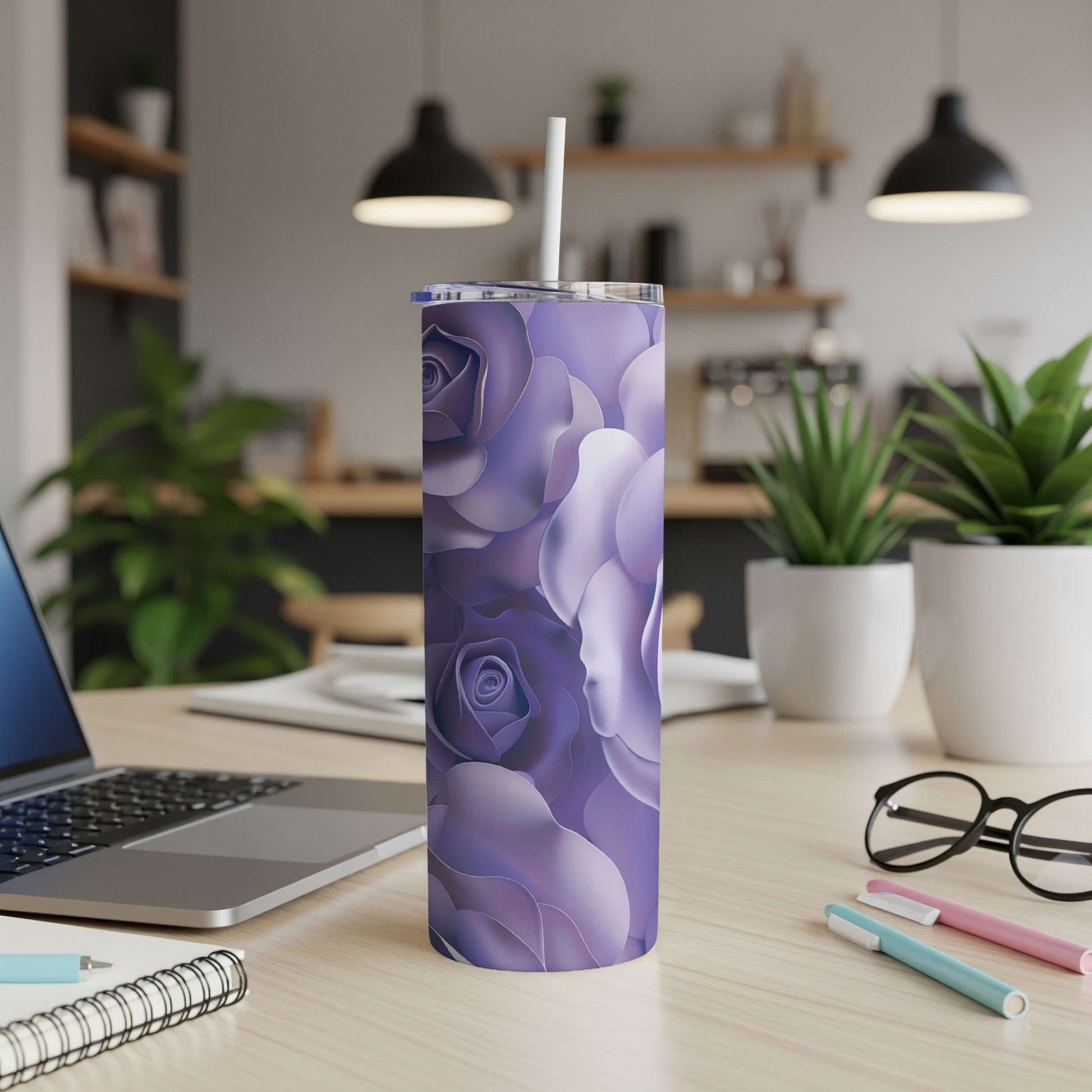 Purple rose floral tumbler with straw on desk with laptop and pens.