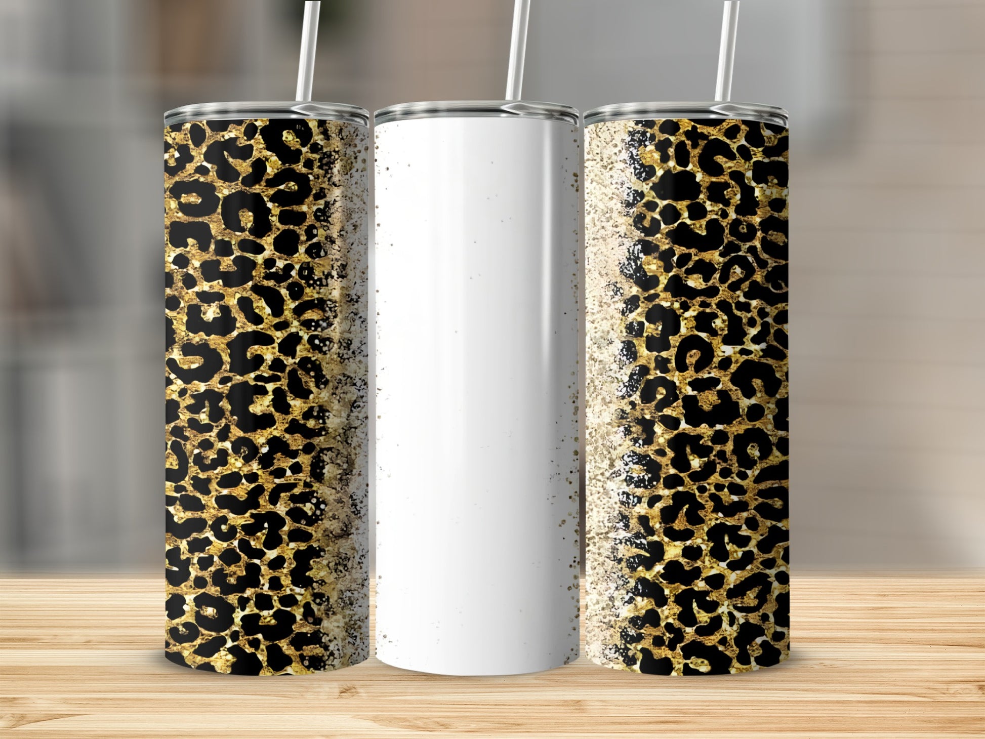 Three leopard print tumblers with straw on wooden surface.