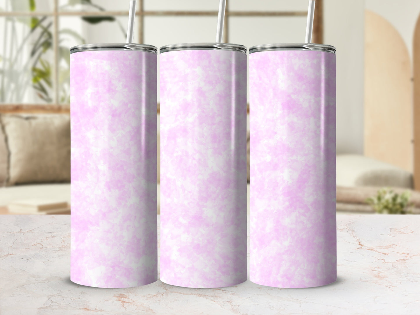 Three pink marbled tumblers with straws on a countertop.