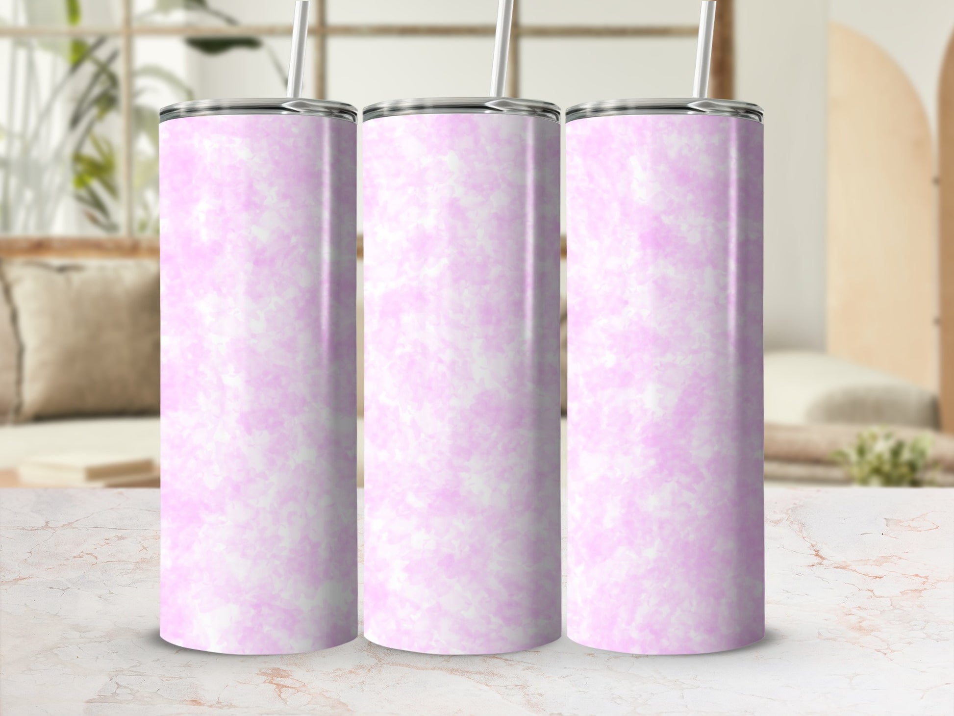 Three pink marbled tumblers with straws on a countertop.