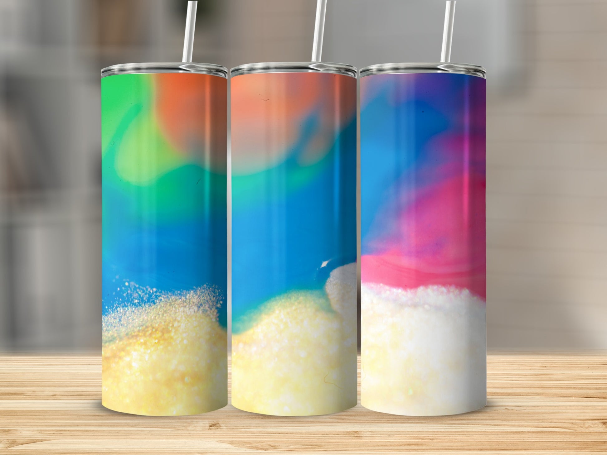 Three tumblers with colorful abstract designs on a wooden surface.