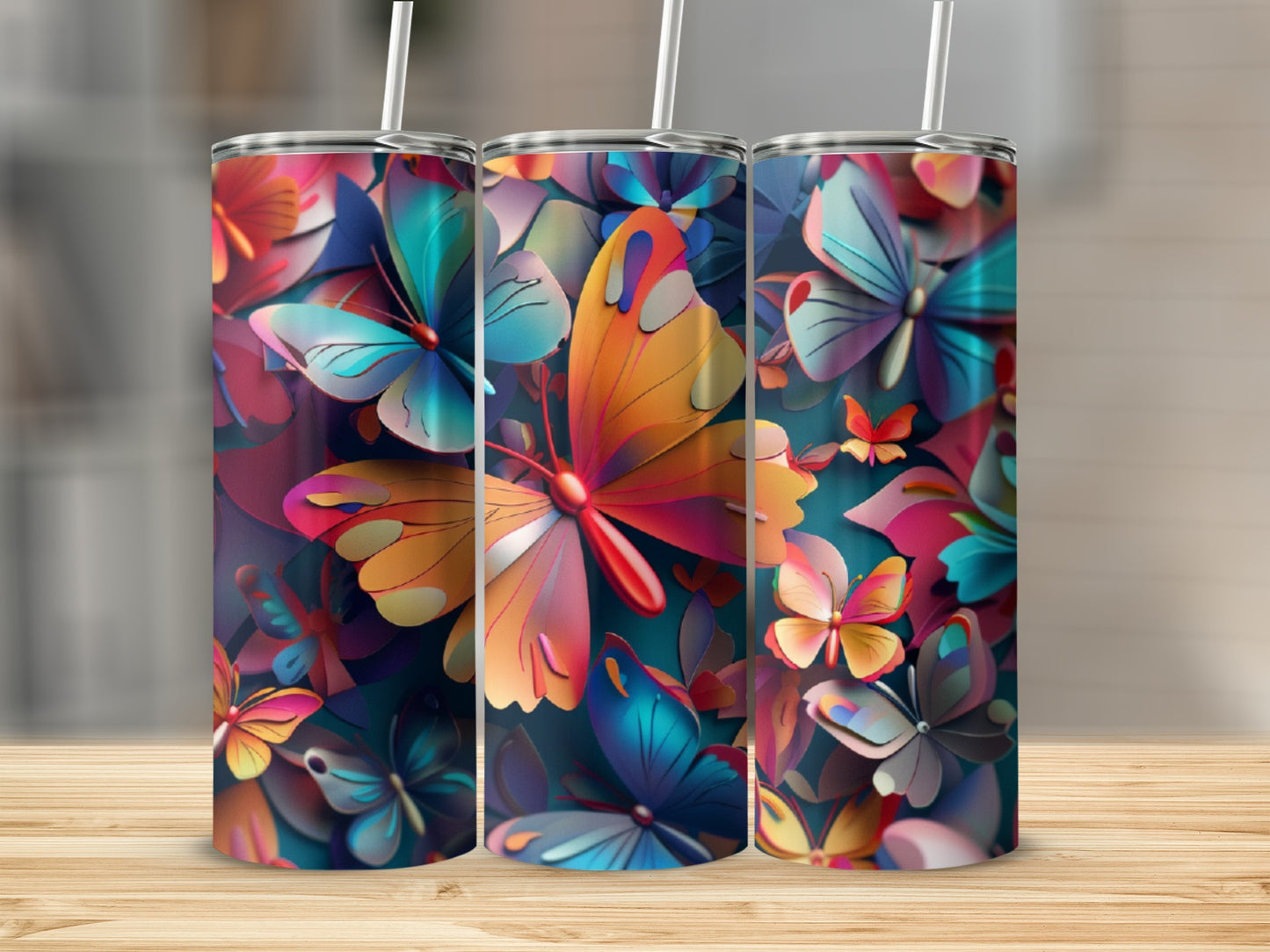 Three tumblers with colorful butterfly designs on a wooden surface.