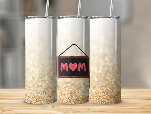 Three glitter tumblers with "Mom" and heart design on a wooden surface.