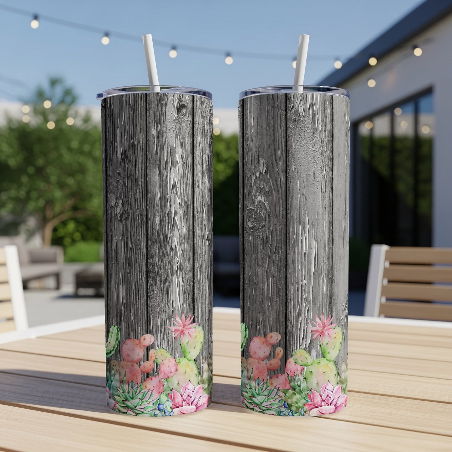 Two insulated tumblers with cactus and floral design on weathered wood background.