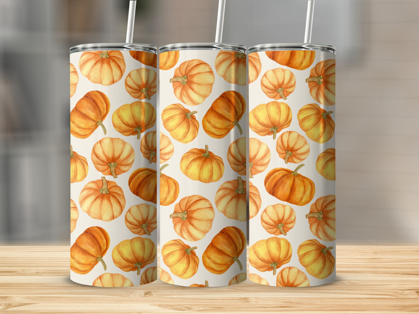 Three tumblers with a repeating pattern of watercolor pumpkins on a wood surface.