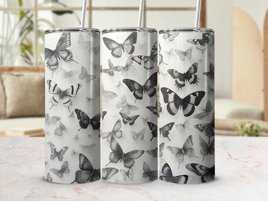Three tumblers with a grayscale butterfly pattern against a blurred background.