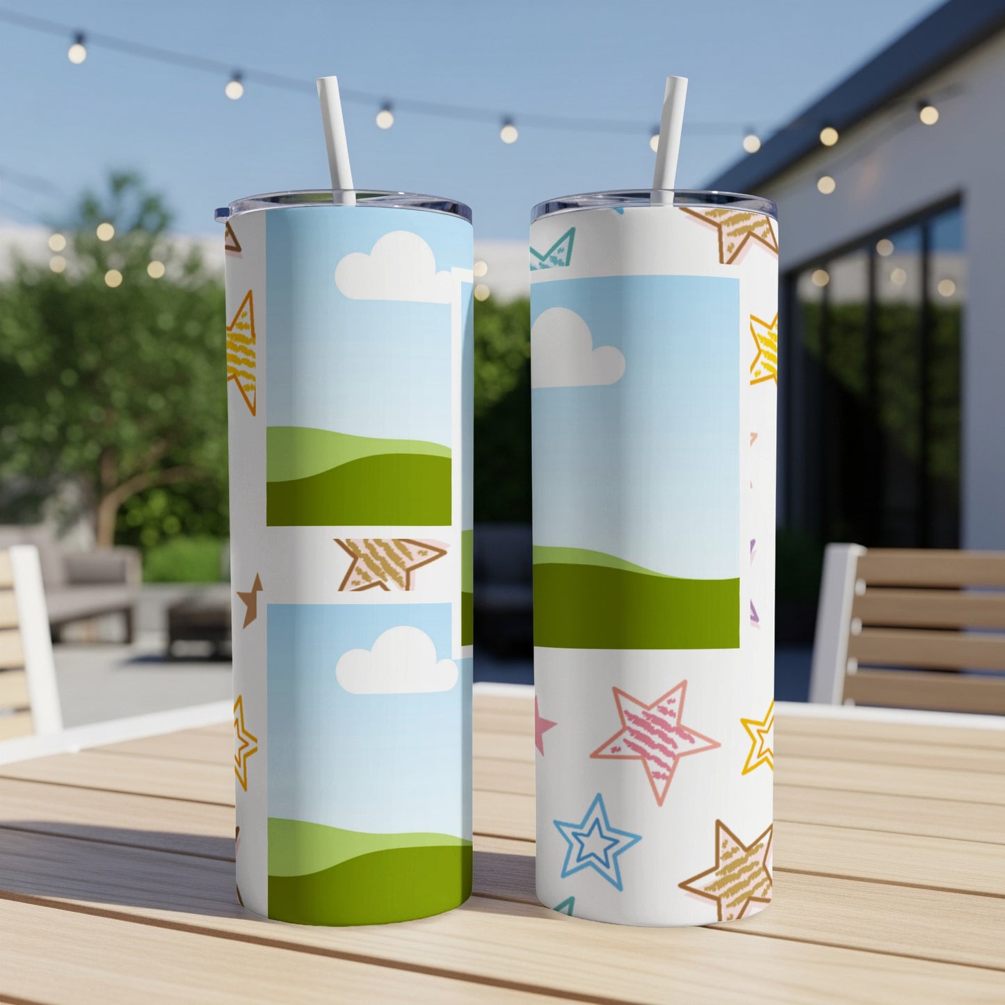 Two tumblers with sky and star patterns sit on a wooden table outdoors.