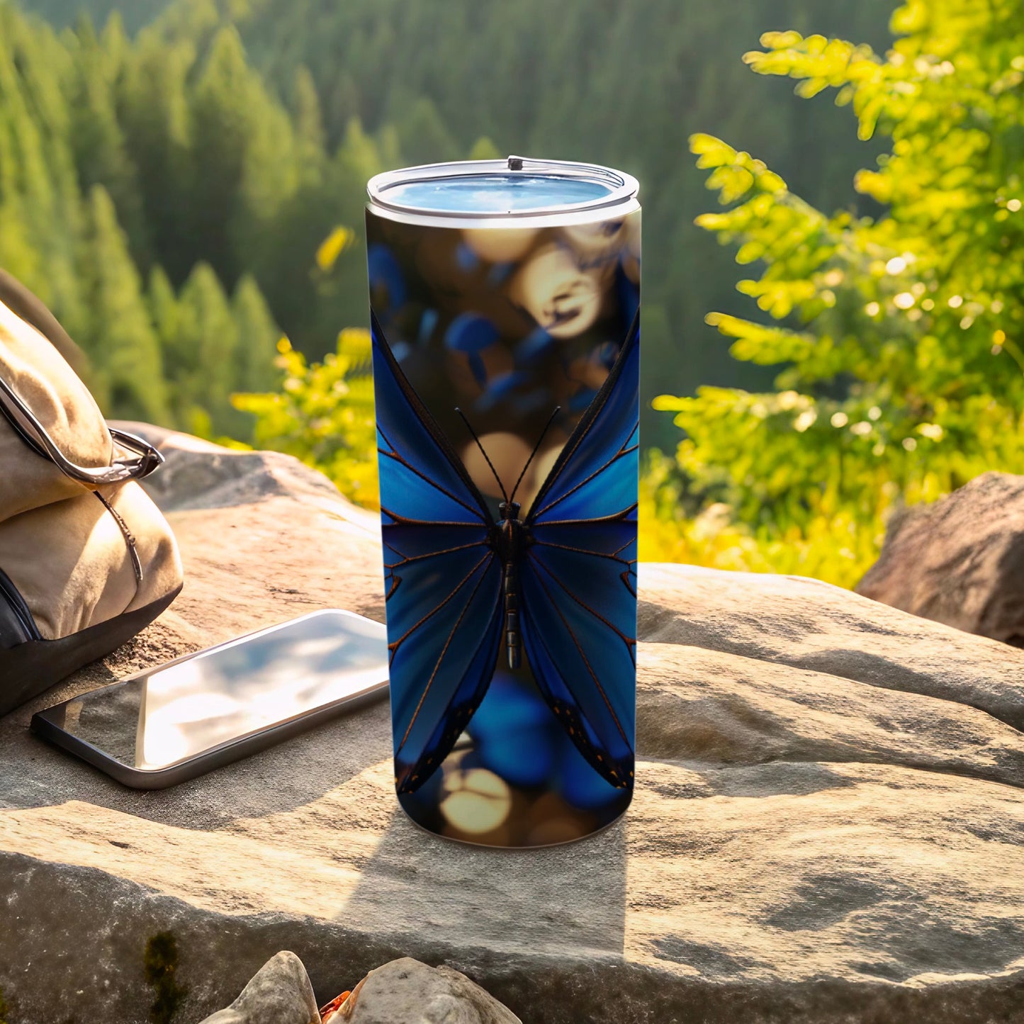 Blue butterfly design on a stainless steel tumbler with blurred forest background.