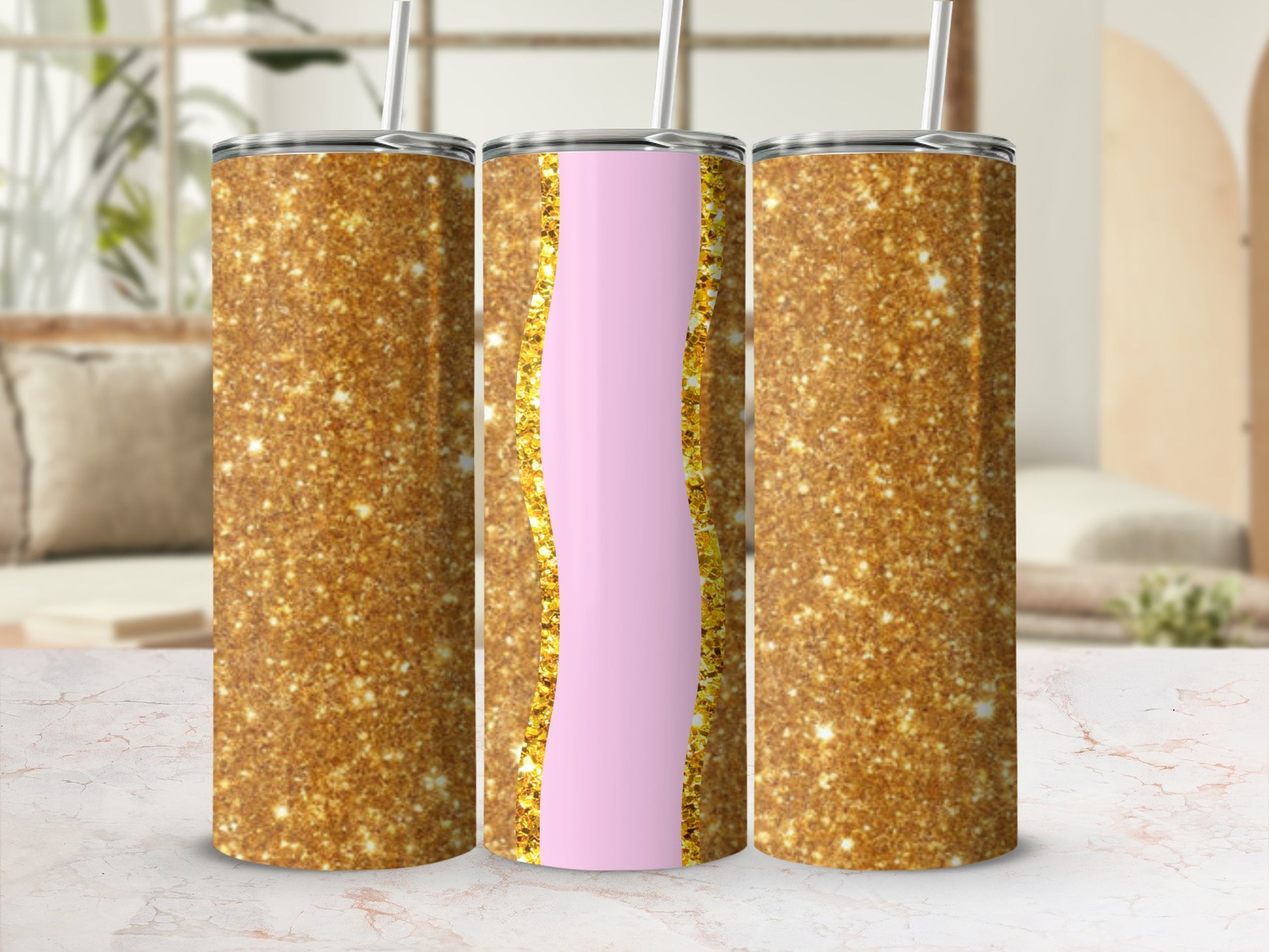 Three gold glitter tumblers with pink accents on a marble surface.