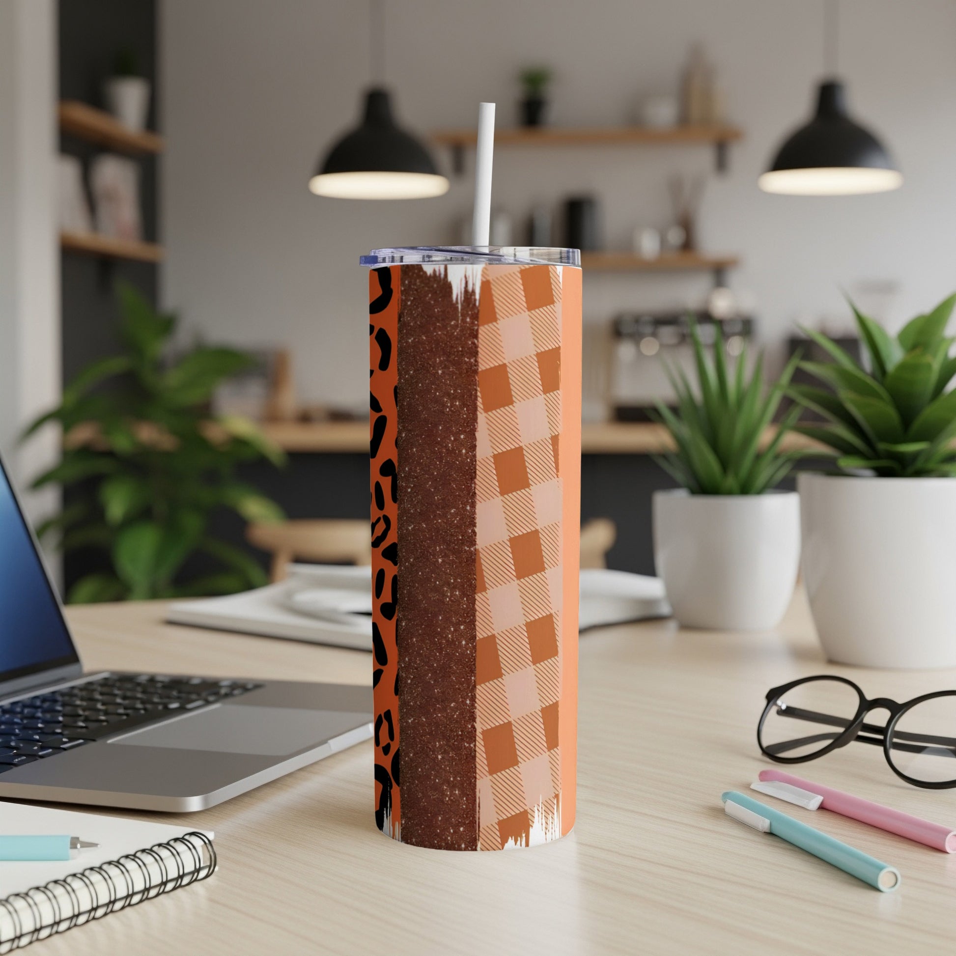 Orange plaid and leopard print tumbler with straw on a desk.