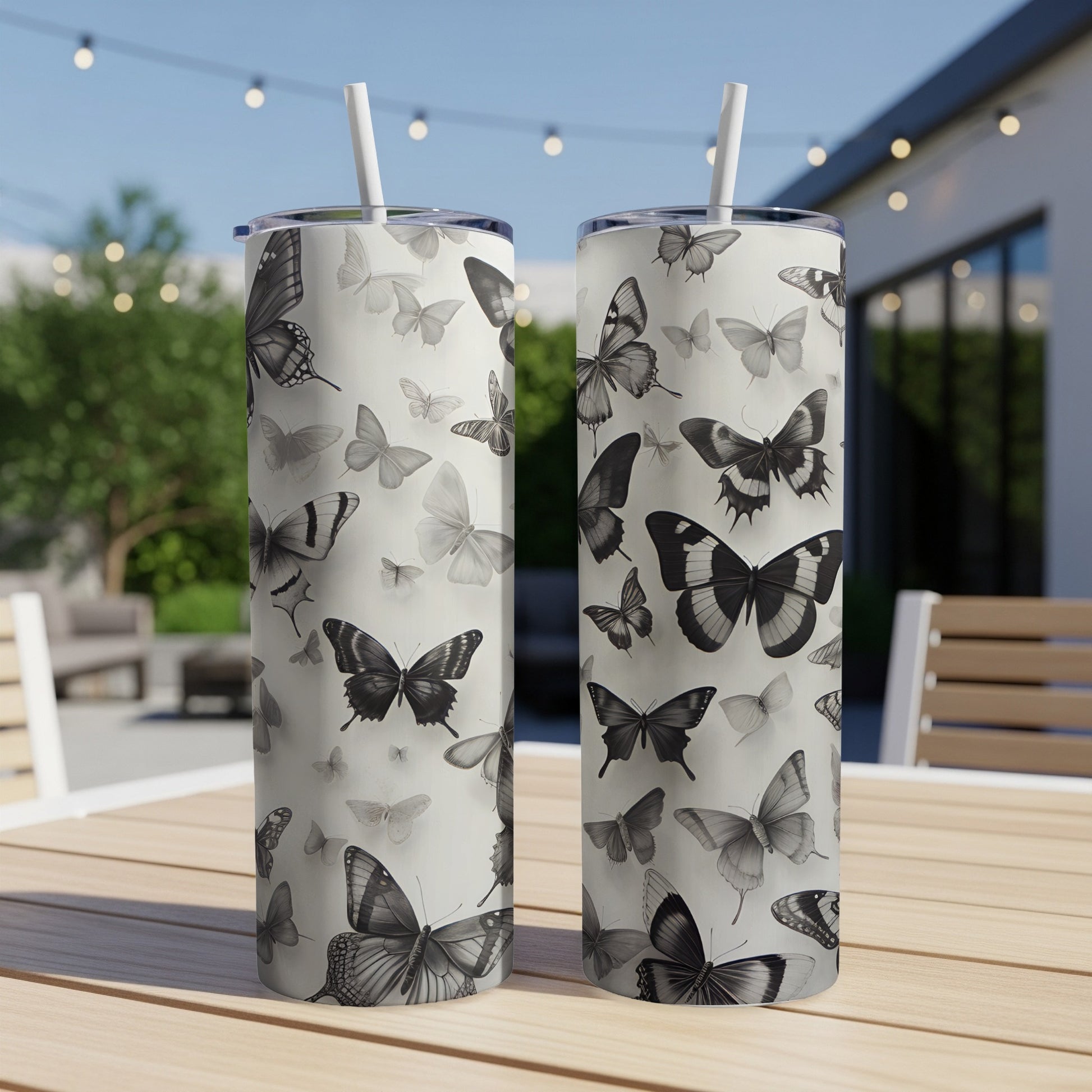 Two patterned tumblers with black and white butterfly designs on a table.