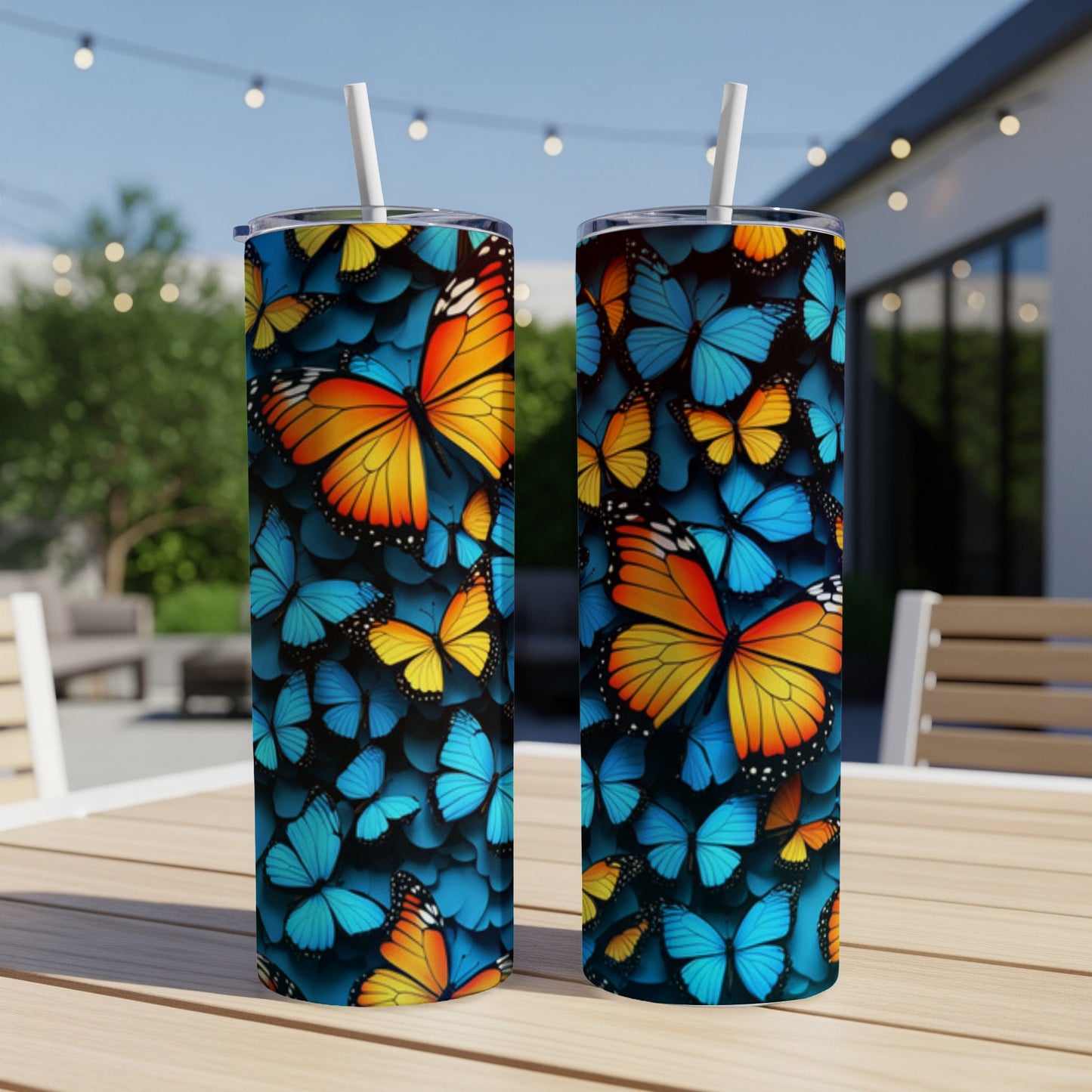 Two tumblers with vibrant orange and blue butterfly patterns on a wooden table.