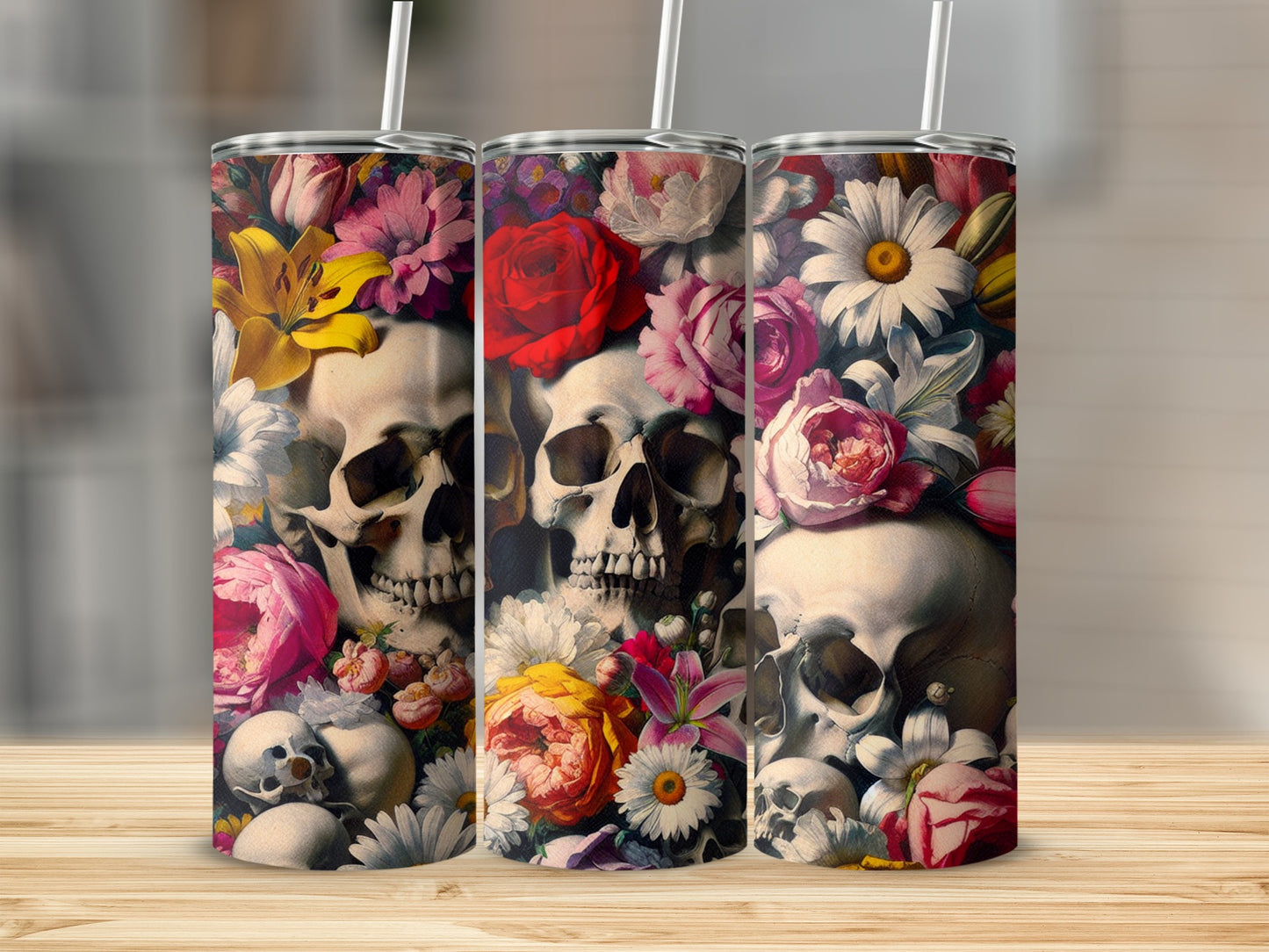 Three tumblers with floral skull designs on a wooden surface.