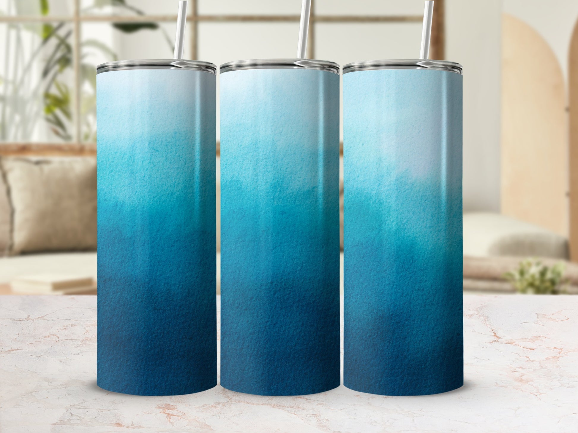Three gradient tumblers with ombre blue and white designs and straws.