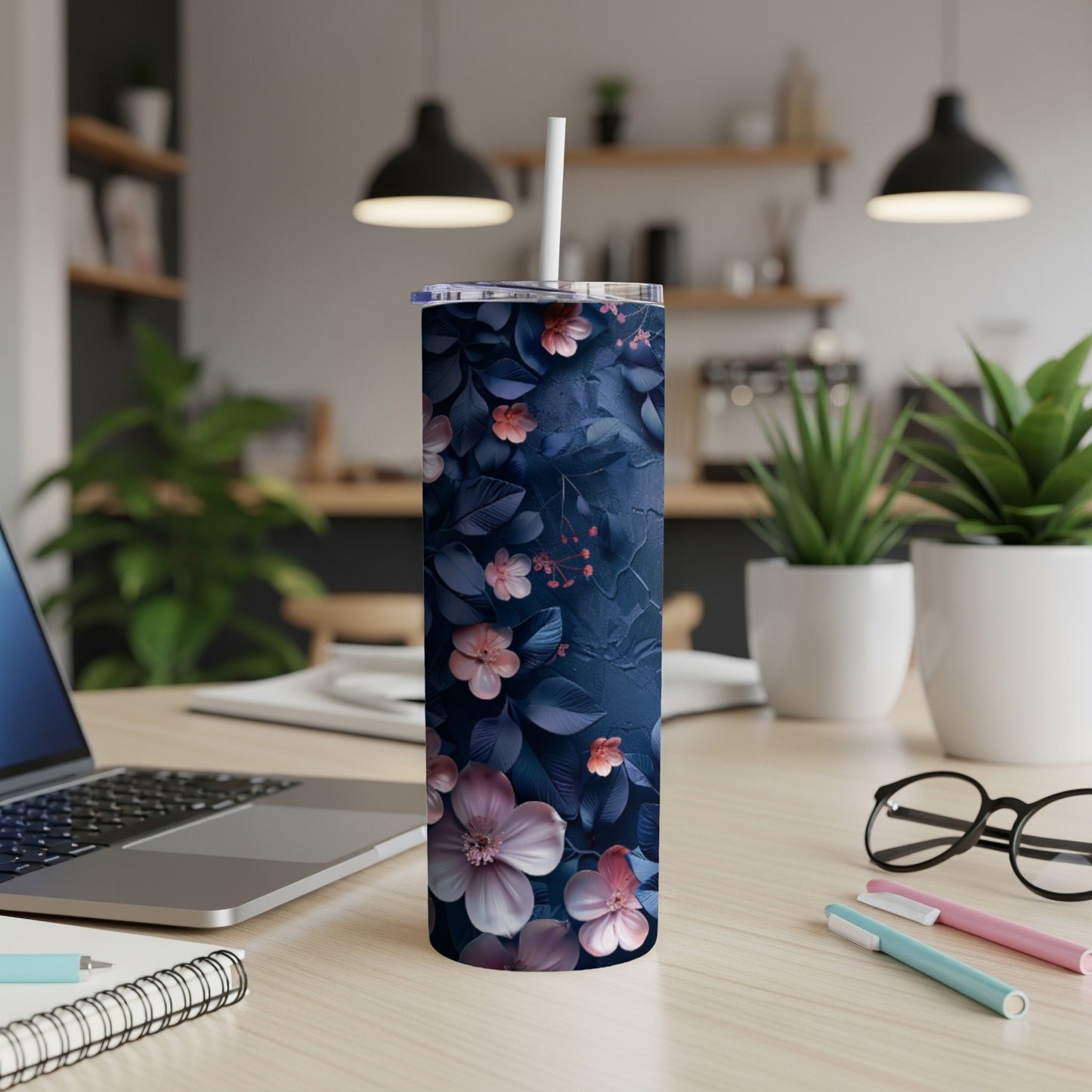 Dark blue tumbler with pink and purple floral pattern on a wooden desk.