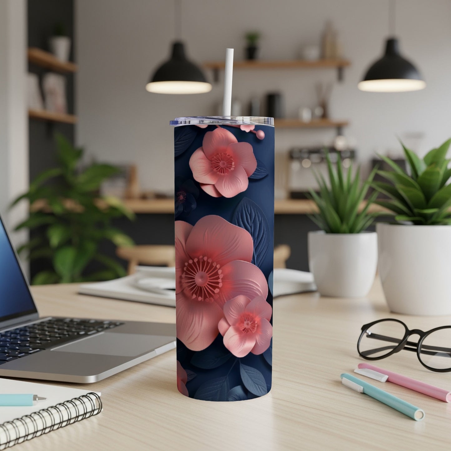Dark navy tumbler with pink floral design, on a desk with laptop and pens.