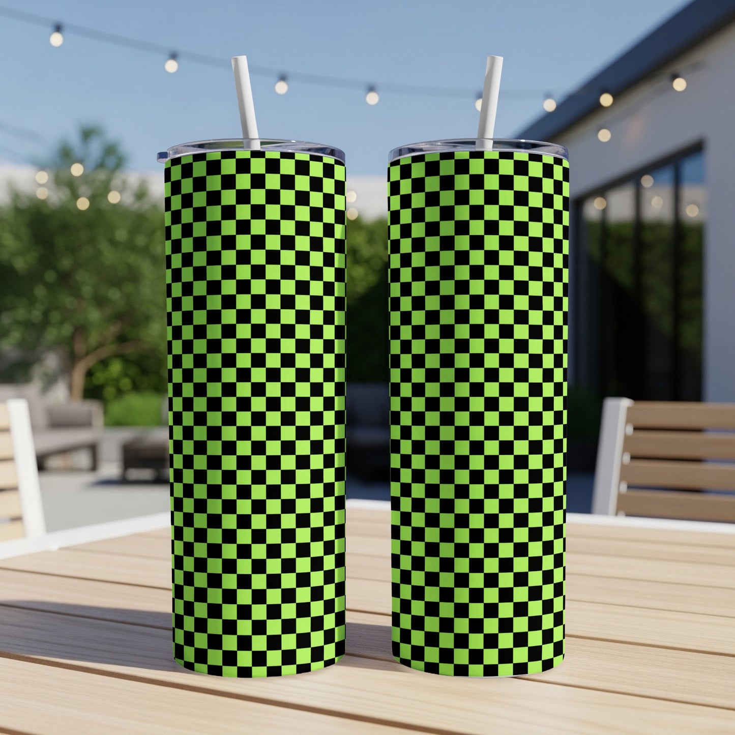 Two neon green and black checkered tall tumblers with straws on a table.