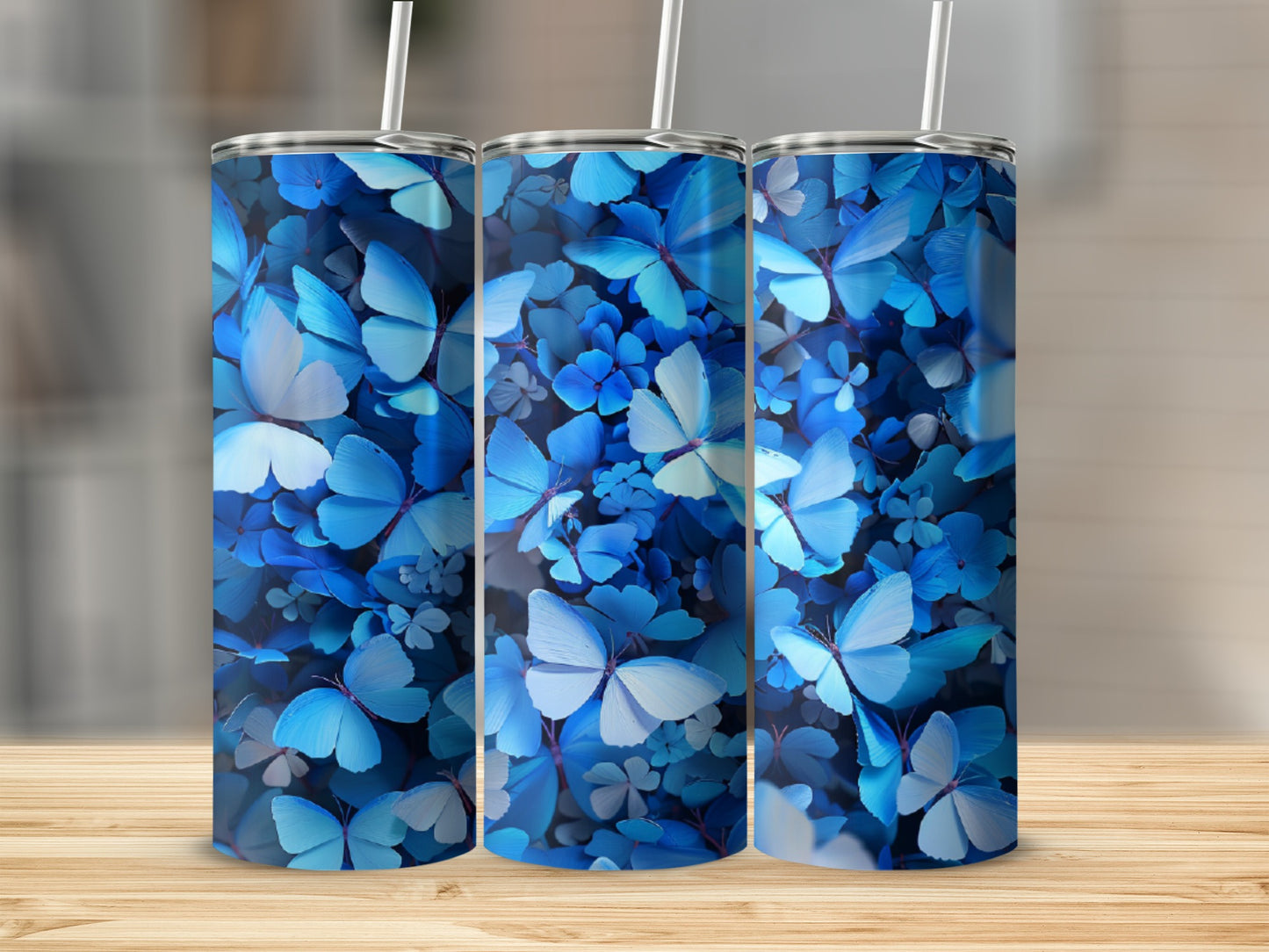 Three blue butterfly tumblers with floral patterns on a wooden surface.