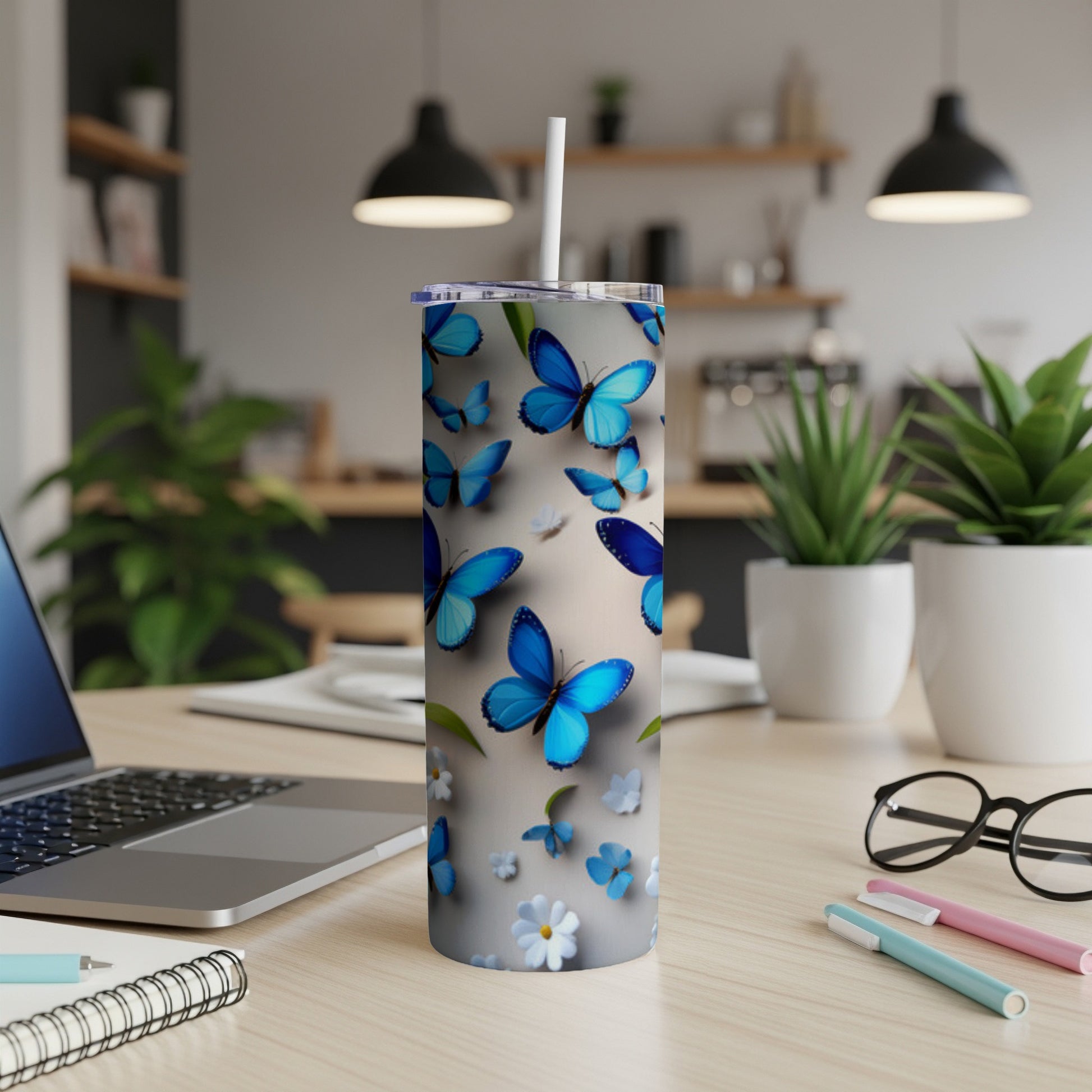 Blue butterflies and flowers on a tall, white tumbler with a straw.