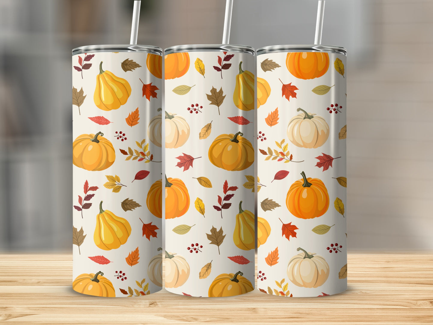 Three tumblers with a fall pumpkin and leaf pattern on a wooden surface.