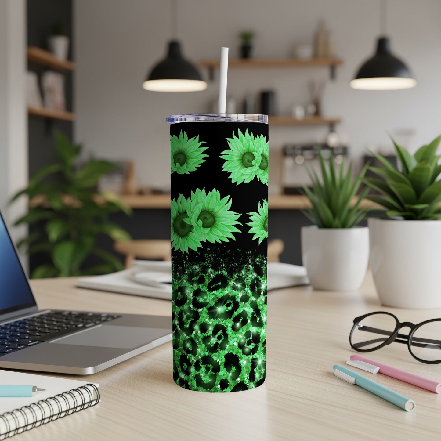 Green floral and leopard print tumbler with straw on a desk.