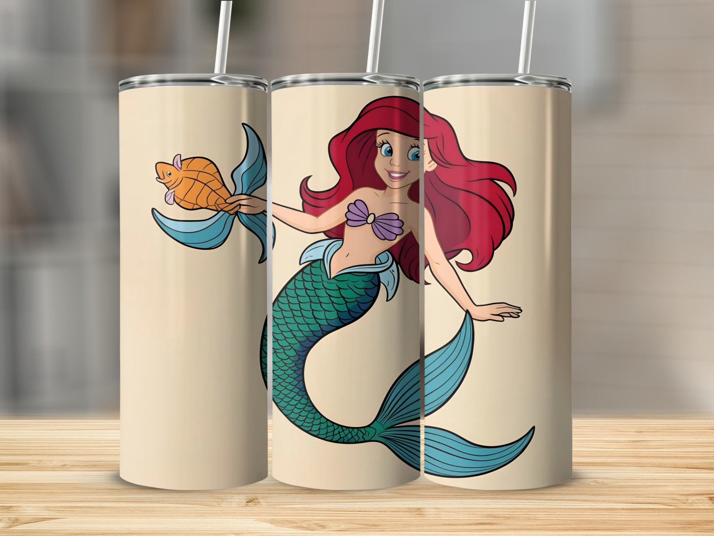 Ariel the mermaid holds a gold fish, with three tumblers displayed.
