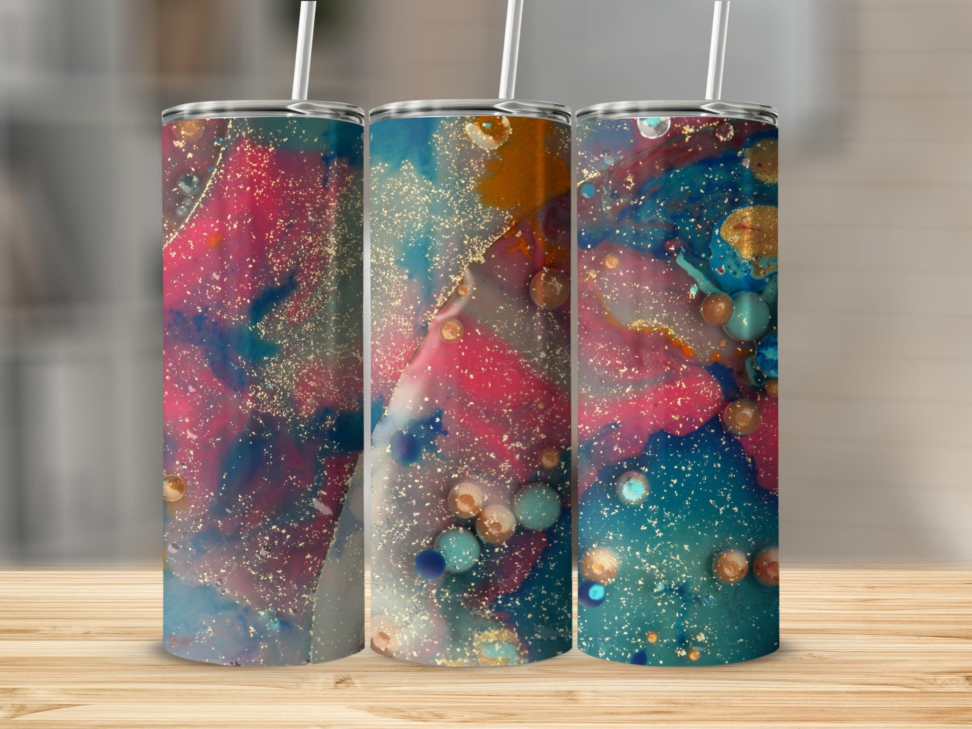 Three tumblers with abstract, colorful paint splatter designs and gold accents.