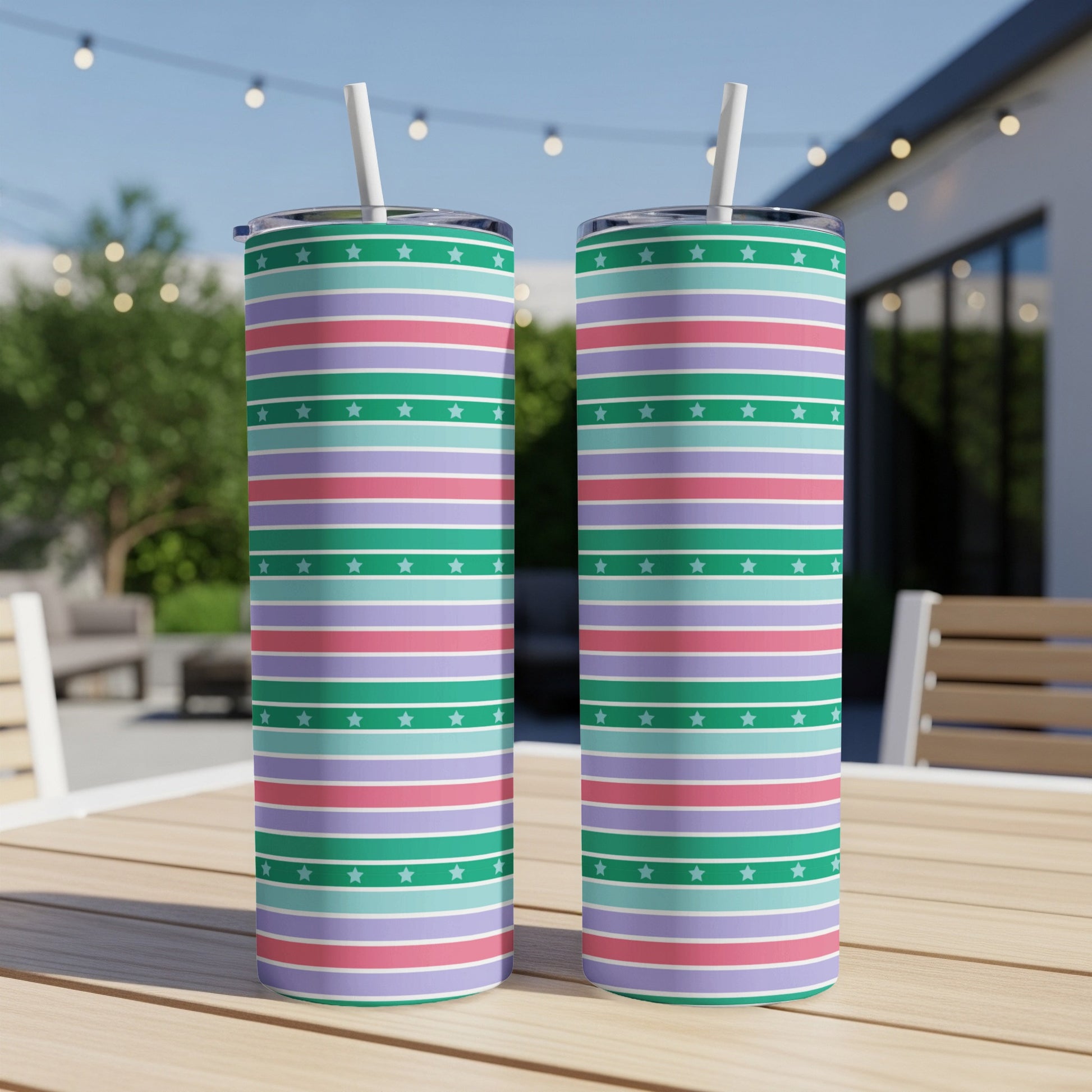 Two striped tumblers with straws on a table.