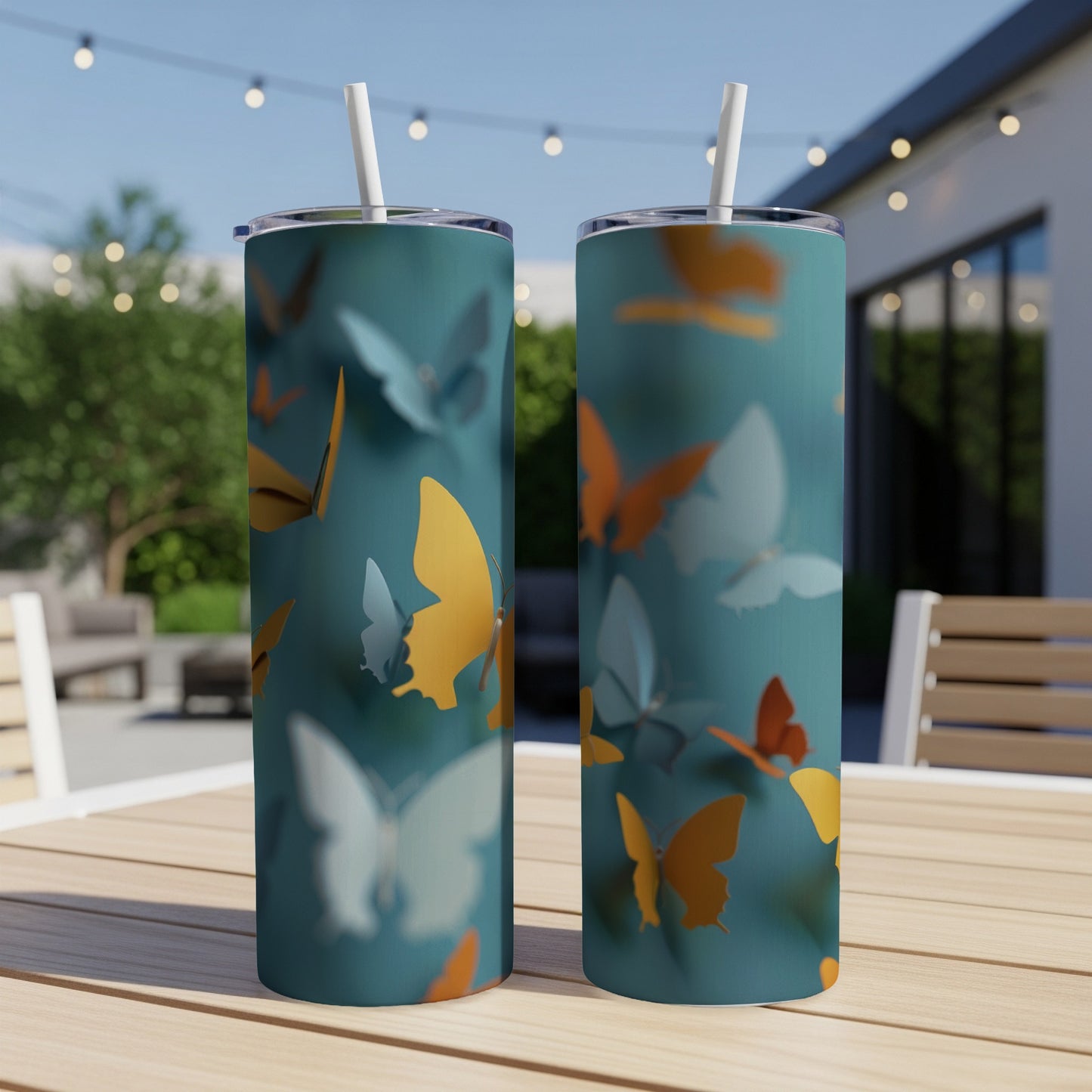 Two teal tumblers with orange and yellow butterflies, straw in each.