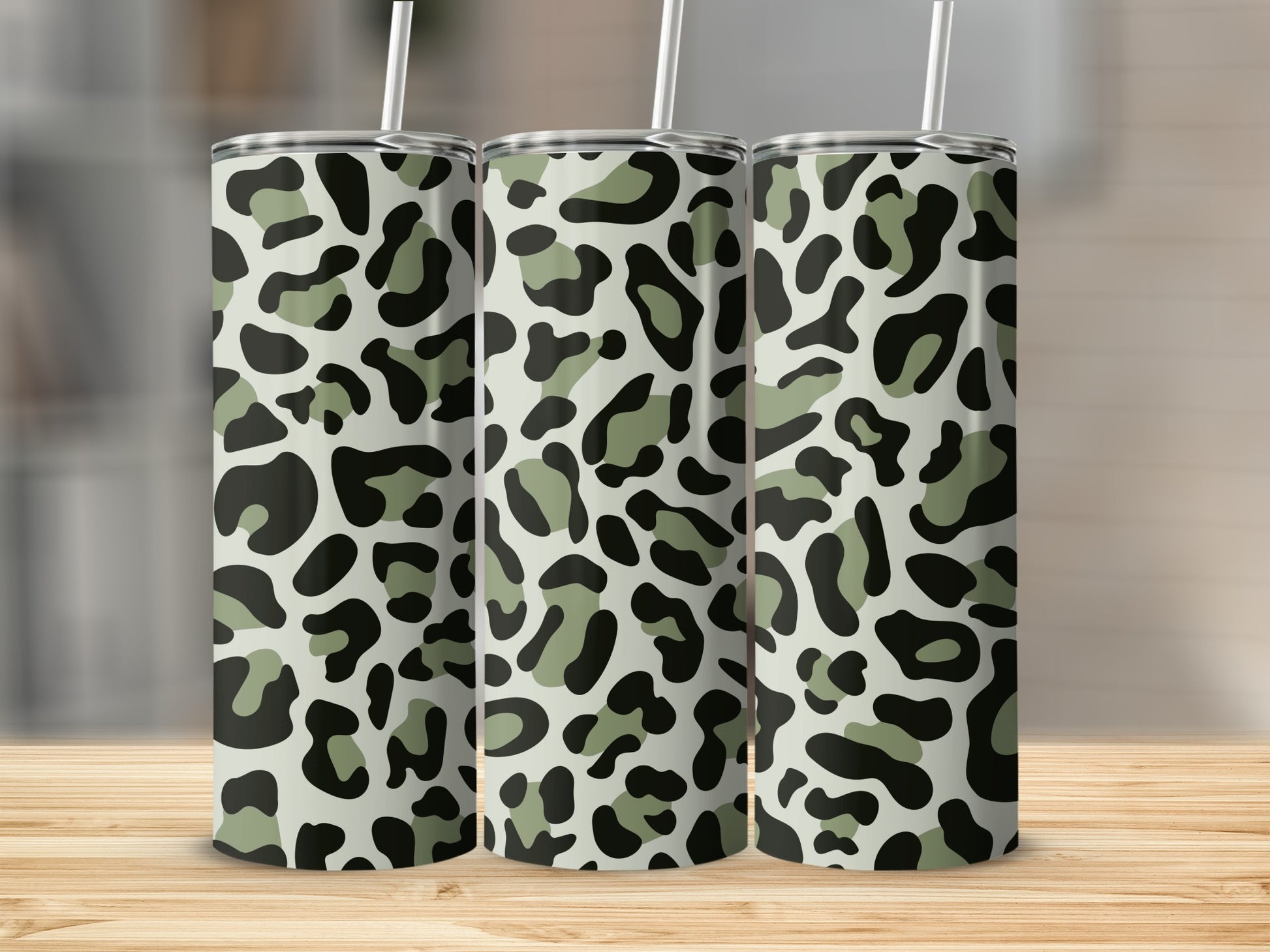 Three tumblers with a camouflage leopard print design and white straws.