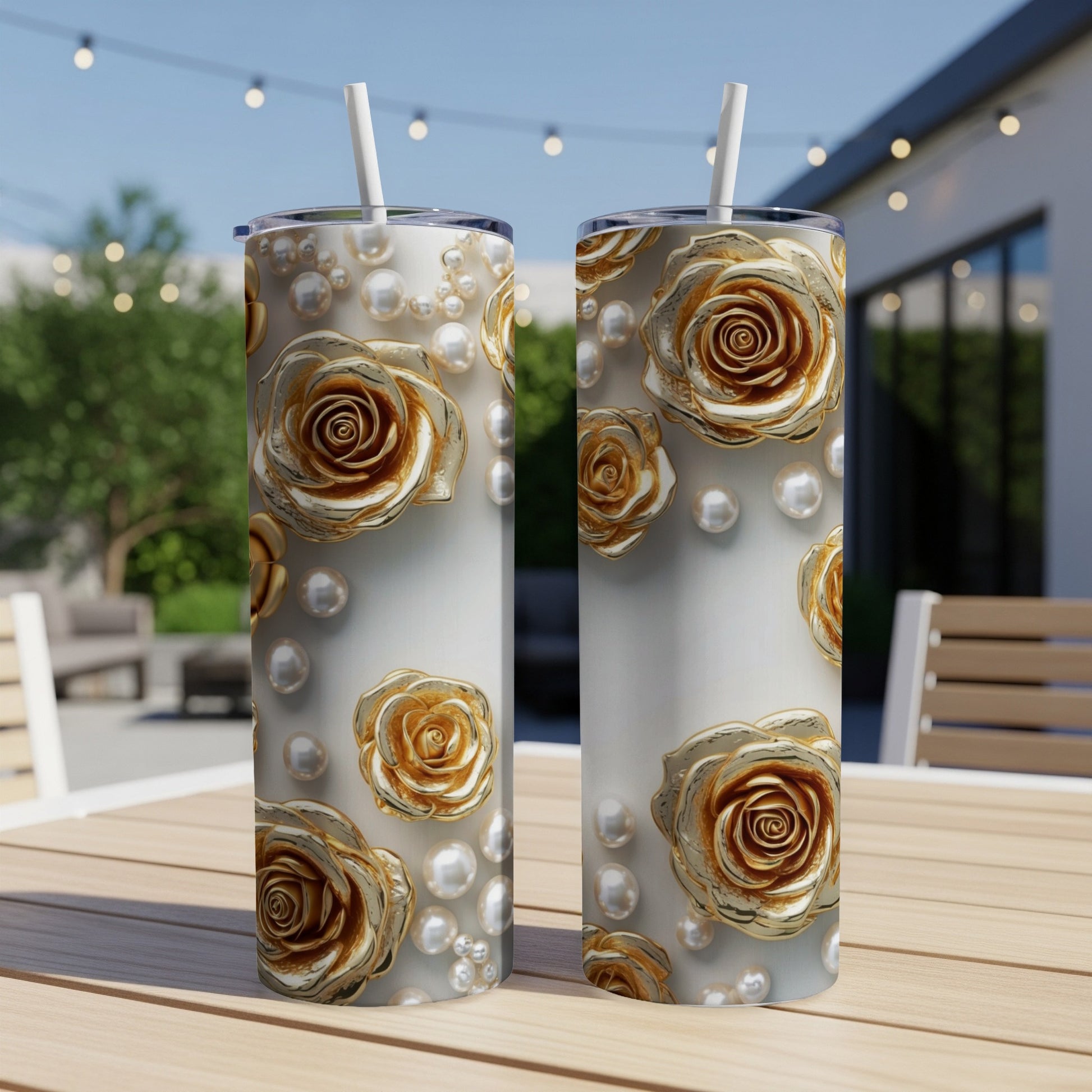 Two white tumblers with gold roses and pearls design on a patio table.