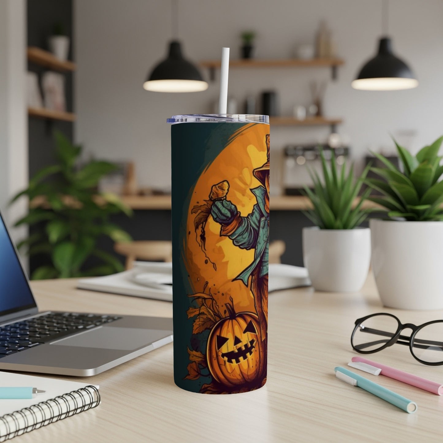 Tumbler with scarecrow and jack-o'-lantern Halloween design, on a desk.
