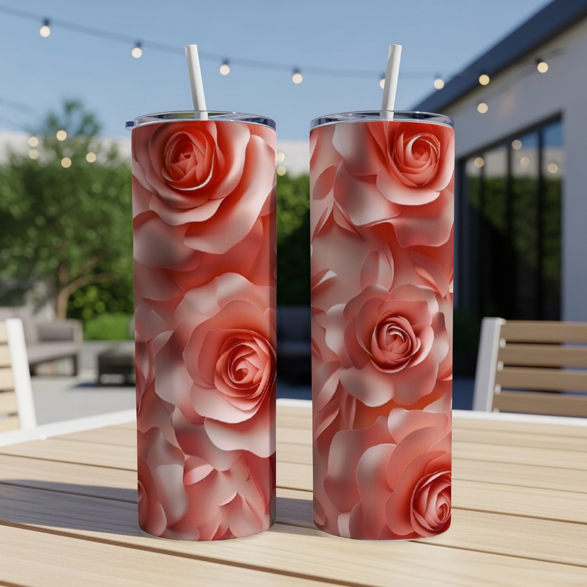 Two tall tumblers with a rose floral pattern on a wooden table outdoors.