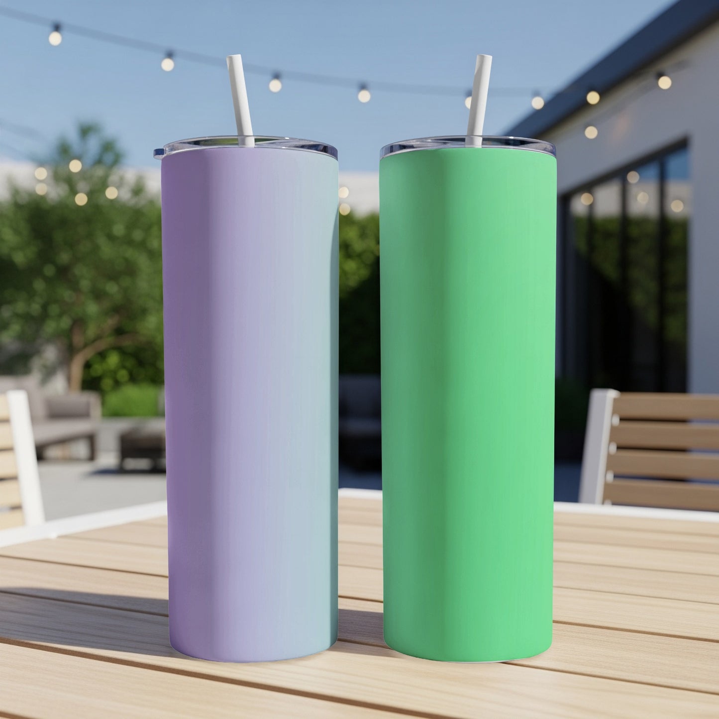 Two stainless steel tumblers, green and purple, on a wooden table outdoors.